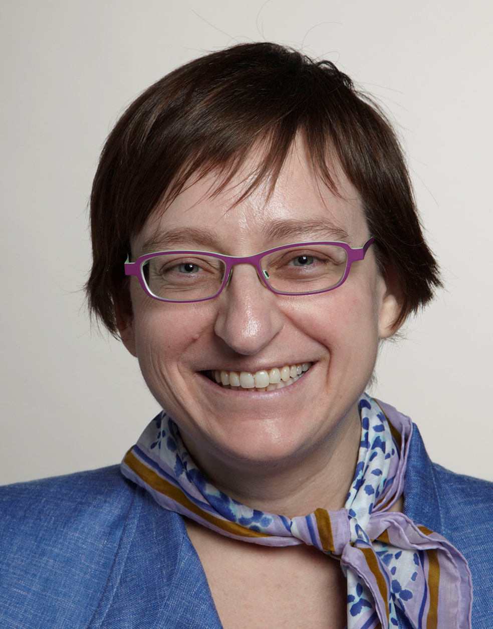 Patricia Kovatch, wearing glasses and smiling at the cameraDescription automatically generated